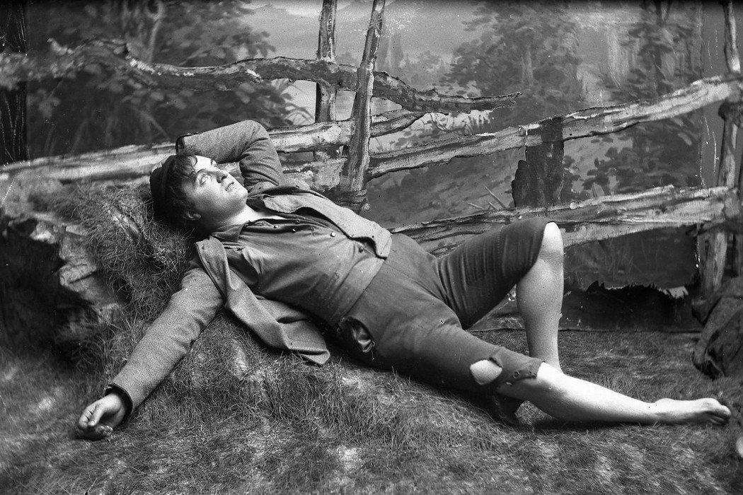 An actor portraying the fiction character Peer Gynt lying in the gras. 