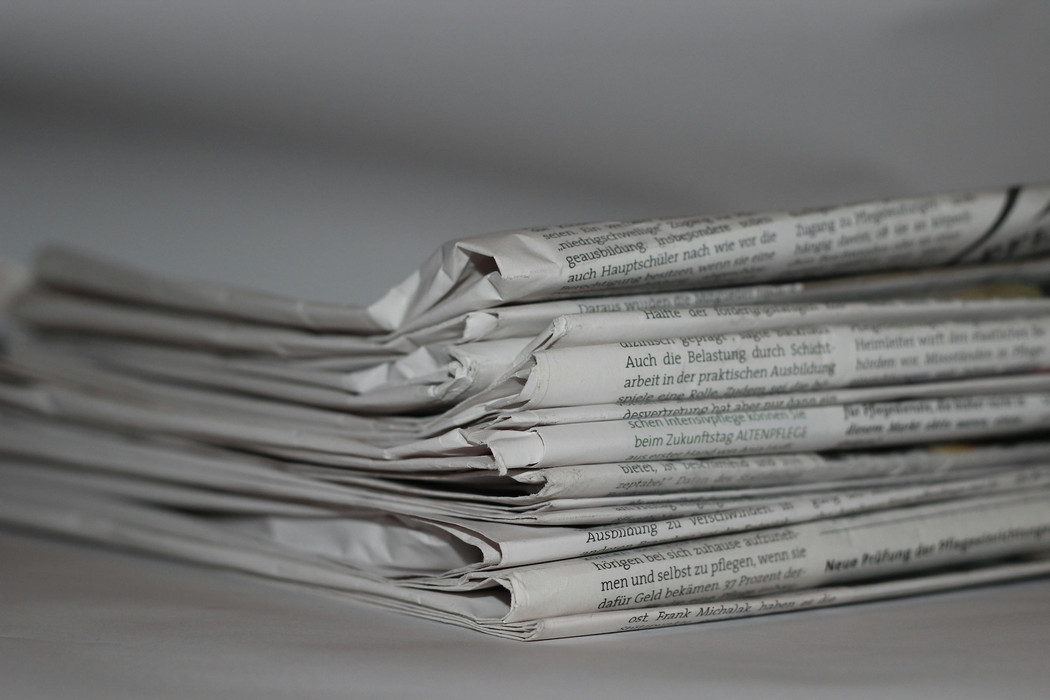 A stack of folded newspaper, black and white photo. 